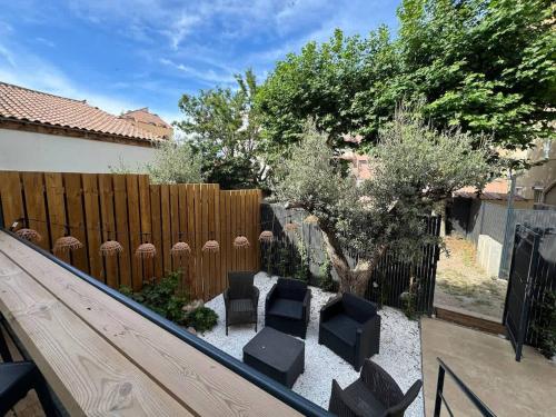 une cour arrière avec une clôture en bois, des chaises et un arbre dans l'établissement Villa Paradis 2 Soleil Mer Plage, à Valras-Plage
