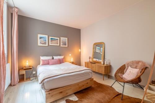 une chambre avec un lit, un miroir et une chaise dans l'établissement Romy - En centre-ville, à Biarritz