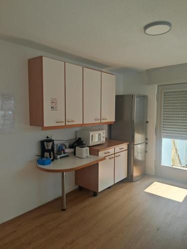 a kitchen with white cabinets and a table and a refrigerator at Monteurzimmer Mühlheim am Main Nähe S-Bahn in Mühlheim
