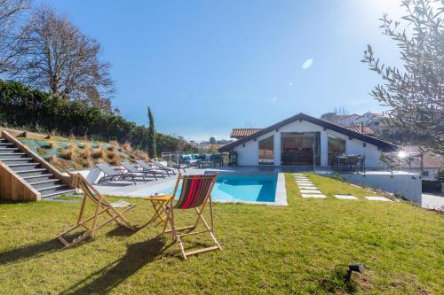 kilka krzeseł siedzących w trawie przy basenie w obiekcie Villa Olaina - Villa climatisée avec piscine w mieście Saint-Jean-de-Luz