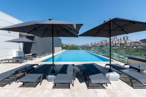 a swimming pool with chairs and umbrellas on a building at Rusel Park Residence in Bahcesehir