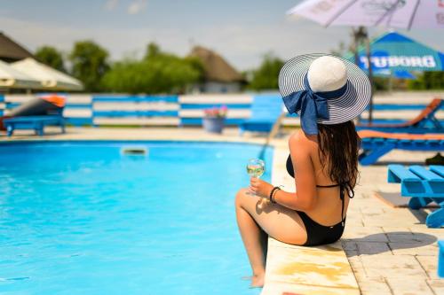 Una mujer en bikini sentada junto a una piscina. en Pensiunea La Sorin, en Murighiol
