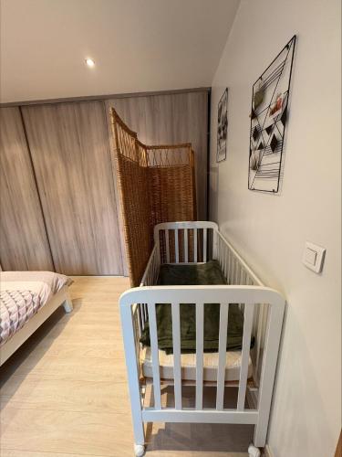 a baby crib in a room with a bed at Appartement 2 chambres Proche CV in Pontarlier