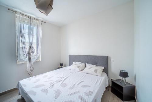 une chambre blanche avec un lit et une fenêtre dans l'établissement Villa Welcom 4 - 2min à Pied de la Plage, à Canet