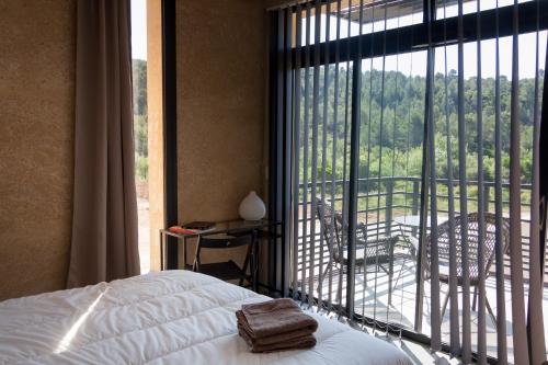 une chambre avec un lit et une vue sur un balcon dans l'établissement Gîte au cœur des vignes, vue sur le Minervois, à Bize-Minervois