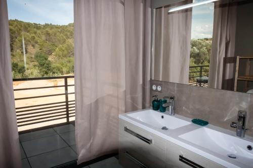 une salle de bain avec un lavabo et une grande fenêtre dans l'établissement Gîte au cœur des vignes, vue sur le Minervois, à Bize-Minervois