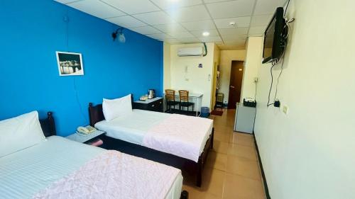 a room with two beds and a blue wall at Magaixian Homestay in Dongyin