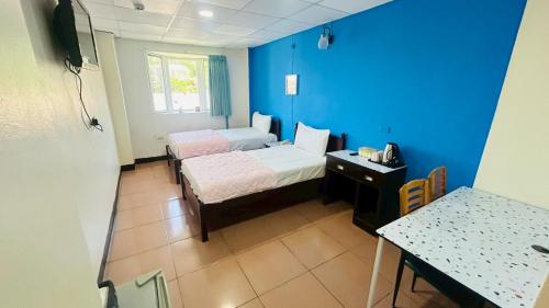 a blue room with two beds and a table at Magaixian Homestay in Dongyin