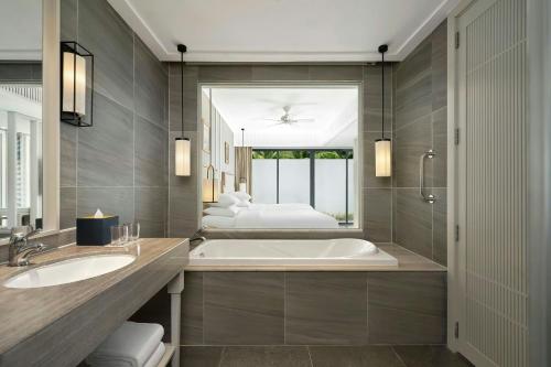 a bathroom with two sinks and a tub with two beds at Renaissance Danang Hoi An Resort & Spa in Hoi An