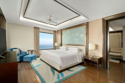 a bedroom with a white bed and a blue chair at Renaissance Danang Hoi An Resort & Spa in Hoi An