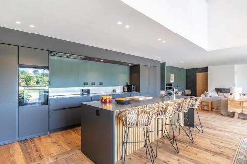 a kitchen and living room with a bar with stools at Villa Loreteian - Splendide villa au calme in Ahetze