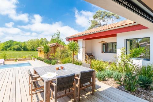 a wooden deck with a table and chairs in a yard at Villa Loreteian - Splendide villa au calme in Ahetze