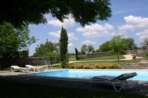 une piscine avec deux chaises longues à côté dans l'établissement Domaine du Château la Rhue grand espace piscine, à Rocamadour