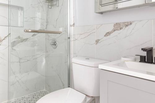 a white bathroom with a toilet and a shower at Blueground Midtown West washerdryer nr Central Park NYC-1877 in New York