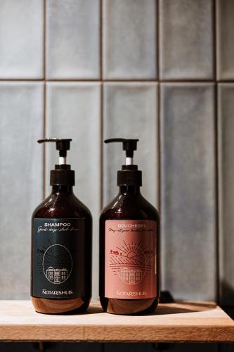 two bottles of soap sitting on a wooden shelf at B&B het Notarishuis - authentiek verblijf nabij Maastricht in Voeren