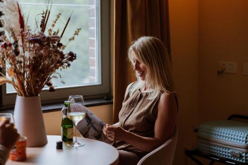 a woman sitting at a table with a glass of wine at B&B het Notarishuis - authentiek verblijf nabij Maastricht in Voeren