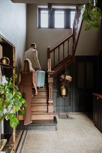 a man and a woman walking down the stairs at B&B het Notarishuis - authentiek verblijf nabij Maastricht in Voeren
