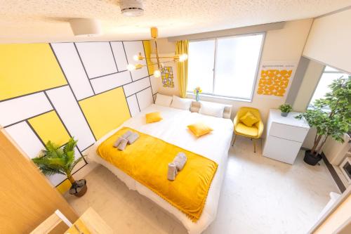 a bedroom with a large bed with a yellow blanket at LEON RESORT HOTEL Makuhari & Tsudanuma Disney & Narita Airport Narashino by LEON RESORT 幕張 津田沼 習志野 in Narashino