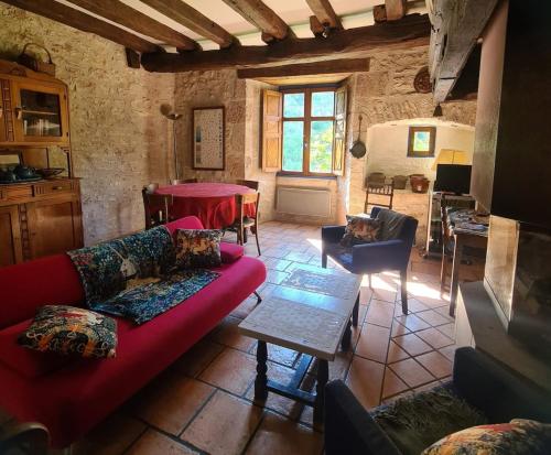 a living room with a red couch and a table at Dans la Cité de Rocamadour L'Oustal de Beline in Rocamadour