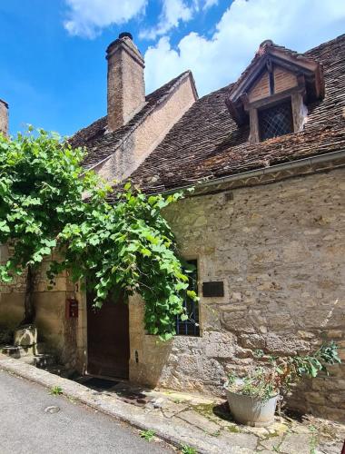 an old stone house with a tree in front of it at Dans la Cité de Rocamadour L'Oustal de Beline in Rocamadour