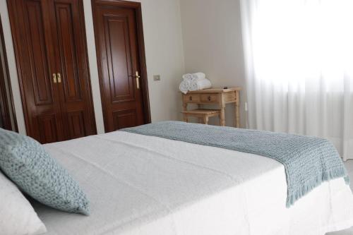a bedroom with a bed with a blue blanket on it at Hotel Alejandrina Poio in Poio