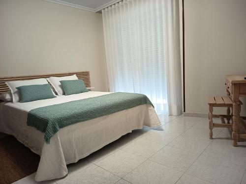 a bedroom with a bed with a green blanket and a window at Hotel Alejandrina Poio in Poio