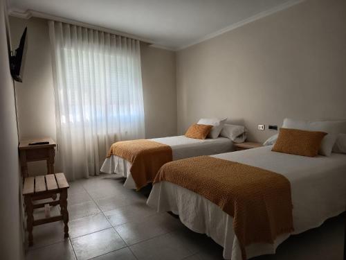 a hotel room with two beds and a window at Hotel Alejandrina Poio in Poio