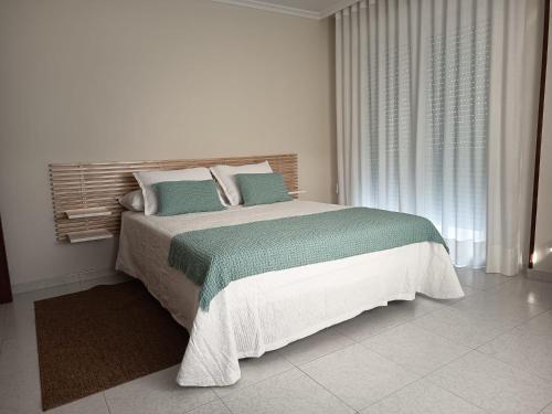 a white bedroom with a large bed with blue pillows at Hotel Alejandrina Poio in Poio