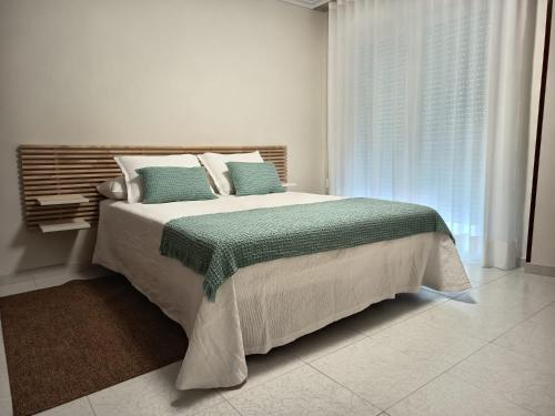a bedroom with a large bed with green and white pillows at Hotel Alejandrina Poio in Poio