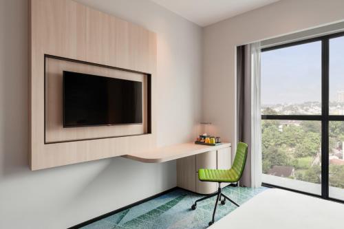 a bedroom with a desk and a tv and a green chair at Holiday Inn Kuala Lumpur Bangsar by IHG in Kuala Lumpur