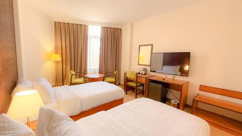 a hotel room with two beds and a television at Aqaba Gulf Hotel By FHM in Aqaba
