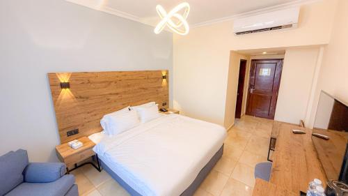 a bedroom with a white bed and a blue couch at Aqaba Gulf Hotel By FHM in Aqaba