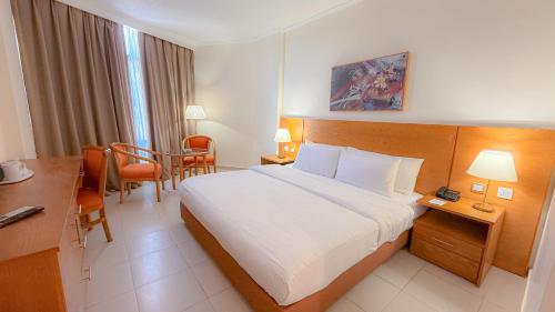a hotel room with a bed and a table and chairs at Aqaba Gulf Hotel By FHM in Aqaba