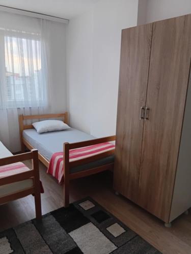 a small bedroom with a bed and a wooden cabinet at Comfort hillside in Pristina