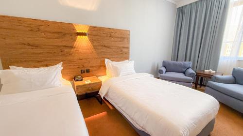 a hotel room with two beds and a chair at Aqaba Gulf Hotel By FHM in Aqaba