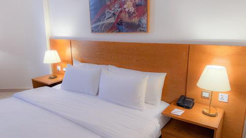 a bedroom with a bed with white sheets and pillows at Aqaba Gulf Hotel By FHM in Aqaba