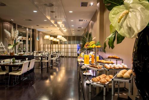 a buffet line with tables and chairs in a restaurant at Hotel Diagonal Plaza in Zaragoza