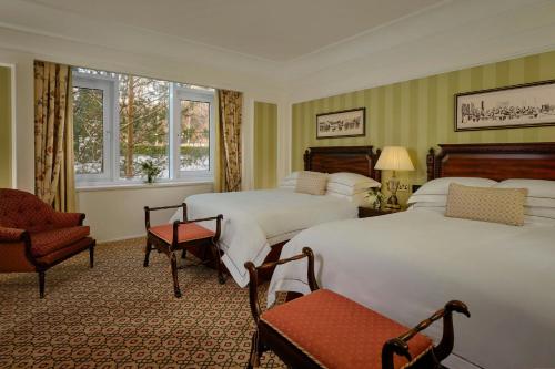 a hotel room with two beds and a chair at Powerscourt Hotel, Autograph Collection in Enniskerry