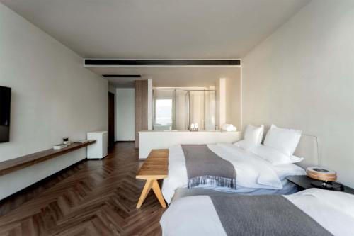 a hotel room with two beds and a television at Dali Qingmai Seaview Resort in Dali