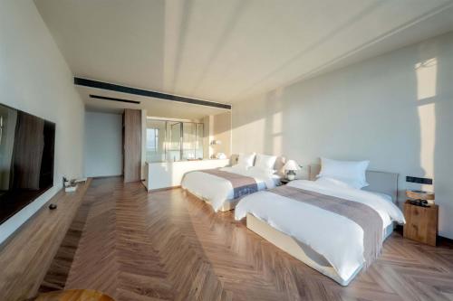 two beds in a large room with wooden floors at Dali Qingmai Seaview Resort in Dali