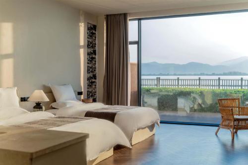 two beds in a hotel room with a large window at Dali Qingmai Seaview Resort in Dali