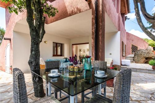 an outdoor dining room with a glass table and chairs at Casa Ortensia in Baja Sardinia