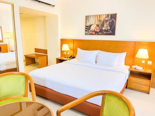 a hotel room with a large bed and two chairs at Aqaba Gulf Hotel By FHM in Aqaba