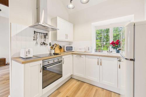 a white kitchen with white cabinets and a window at Host & Stay - Lane Farm Cottage in Easington