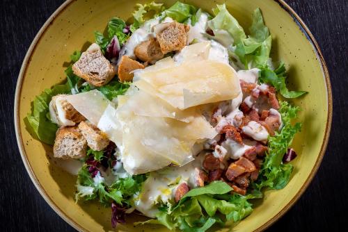 a yellow plate of food with a salad at Hotel Diagonal Plaza in Zaragoza