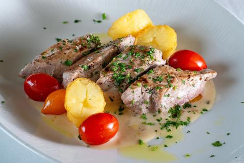 a plate of food with meat and tomatoes on it at Hotel Diagonal Plaza in Zaragoza