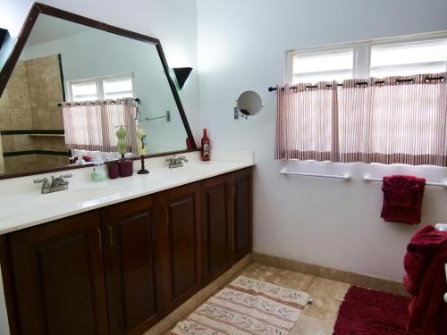 a bathroom with a sink and a large mirror at Villa Luminara- Lux Pool, Garden, Retreat & Beach in Oyster Pond