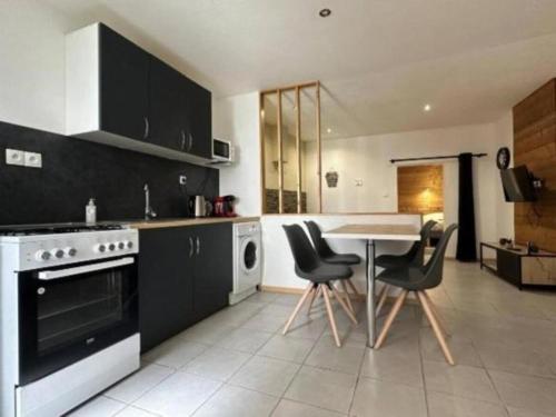 une cuisine avec des armoires noires, une table et des chaises dans l'établissement Le Repaire Sarrecrochet, au Puy-en-Velay