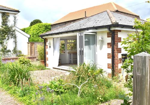 a white cottage with a sliding glass door at Open Plan Dog Friendly Annexe Sleeping 2 I Near Local Beaches & Chichester with FREE Parking in Donnington