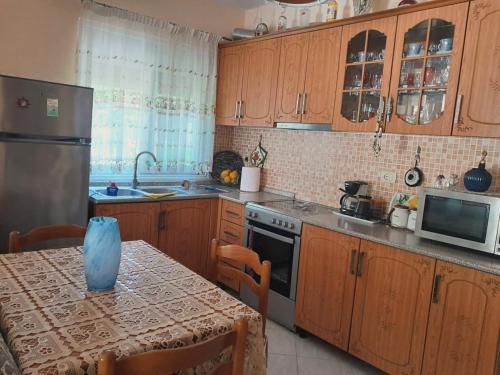 a kitchen with wooden cabinets and a table and a refrigerator at Ylli&Njeza Houses in Vlorë